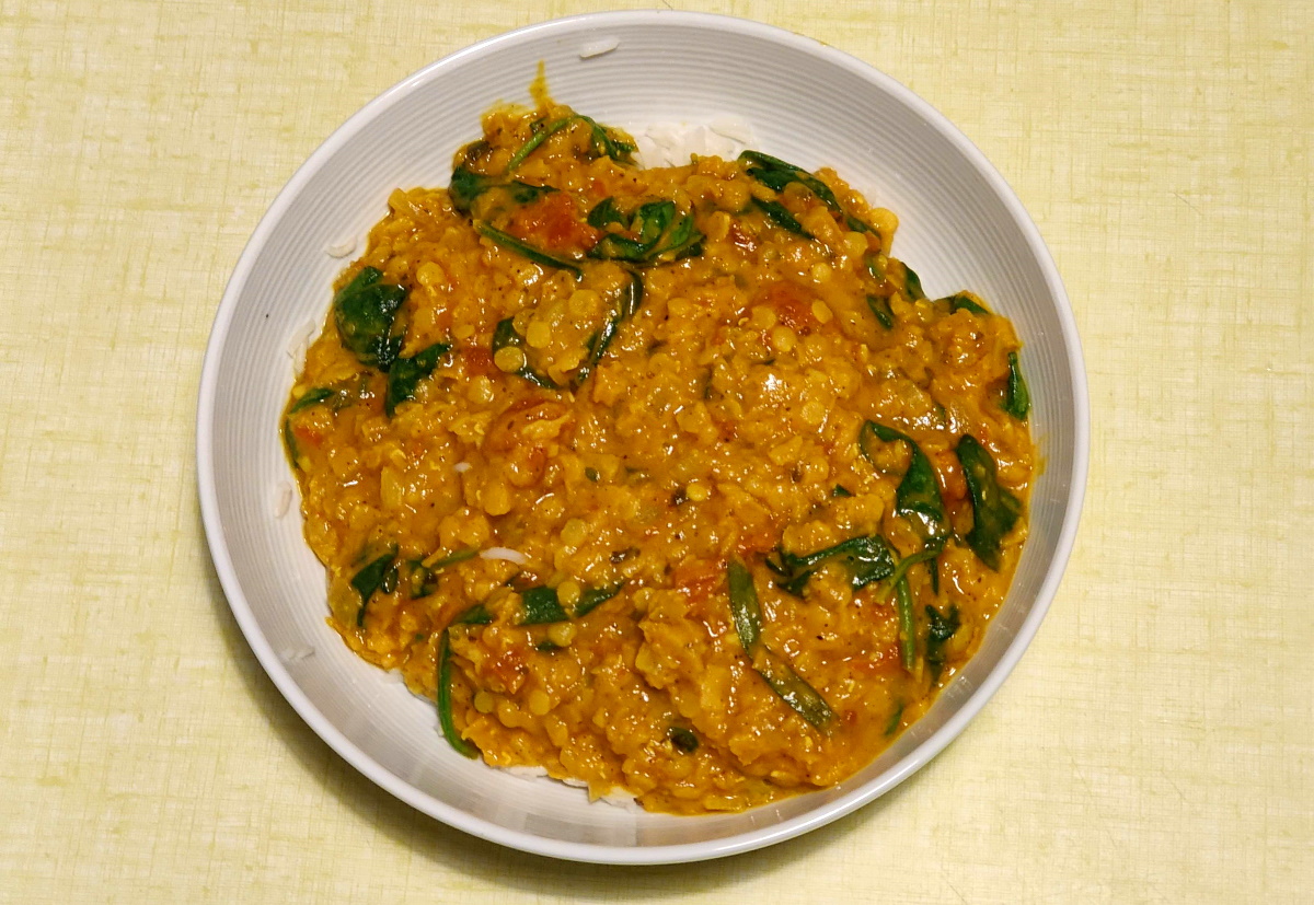 Plat avec un dahl de lentilles corail et épinards en branches (couleurs orangées)